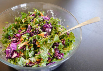 Vegan Crab-Less Cake Kale Salad w/ tomatoes, red onion, purple cabbage, lemon wedge, cilantro creme dressing